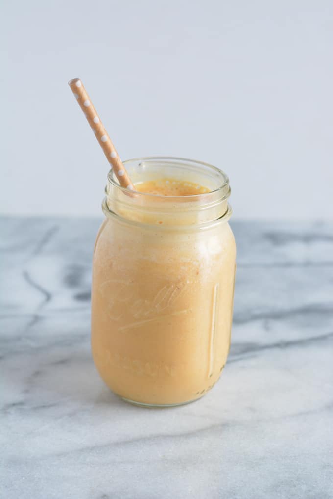 Pumpkin Pie Protein Shake in a mason jar with a straw.