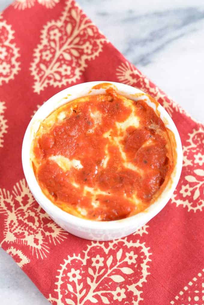 Baked ricotta topped with tomato sauce in a white bowl.