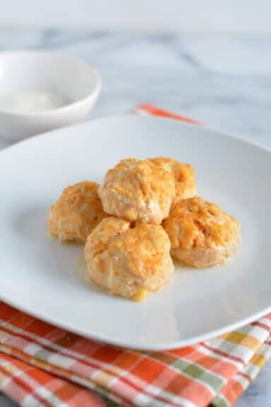 Chicken meatballs with buffalo sauce on a white plate.