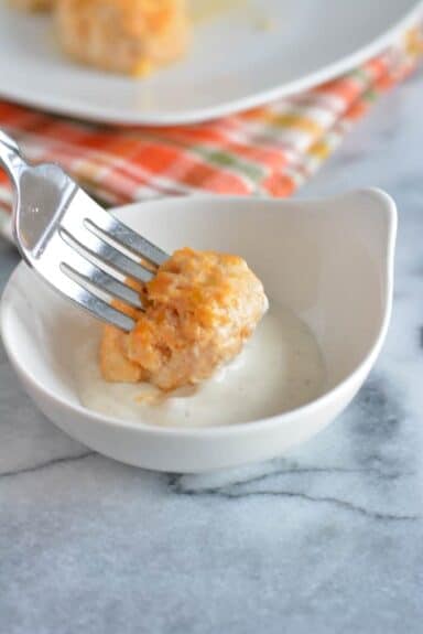 A buffalo meatball on a fork dipped into a dish with ranch dressing.